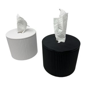 K&ouml;nnte beinhalten: Zwei Taschentuchboxen, eine wei&szlig;e und eine schwarze, jeweils mit einem zylindrischen Rippendesign. Wei&szlig;e Taschent&uuml;cher werden aus der Oberseite jeder Box gezogen. Die Halter sind zum Ausgeben von Taschent&uuml;chern konzipiert.
