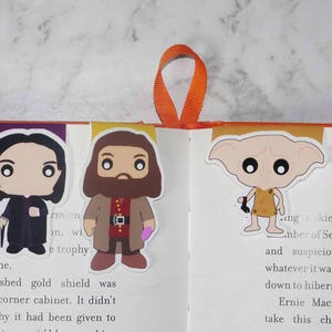 Peut inclure: Cinq marque-pages de personnages d'Harry Potter illustrant Dumbledore, Rogue, Hagrid, Dobby et Voldemort. Les marque-pages sont imprimés sur du papier cartonné blanc et ont une finition brillante.