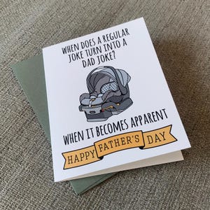May include: A white card with a black and gray illustration of a baby car seat. The card has the text "WHEN DOES A REGULAR JOKE TURN INTO A DAD JOKE? WHEN IT BECOMES APPARENT HAPPY FATHER'S DAY".