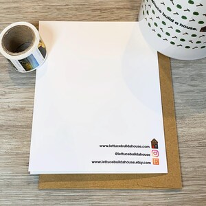 May include: A white card with the text "www.lettucebuildahouse.com", "@lettucebuildahouse", and "www.lettucebuildahouse.etsy.com" printed on it. The card is sitting on a brown envelope.