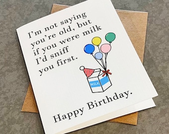 May include: A white card with a birthday message that says "I'm not saying you're old, but if you were milk I'd sniff you first."  The card has a cartoon illustration of a milk carton with a party hat and balloons.