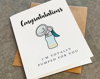 May include: A white greeting card featuring a cartoon illustration of a breast pump in the centre. The text "Congratulations" is printed in black above the illustration, and "I'M TOTALLY PUMPED FOR YOU" is printed in black below the illustration.
