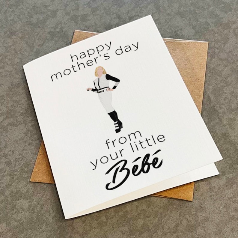 May include: A white card with black text that reads "happy mother's day from your little B&eacute;b&eacute;". A cartoon illustration of a woman in a white jumpsuit and black boots is in the center of the card.