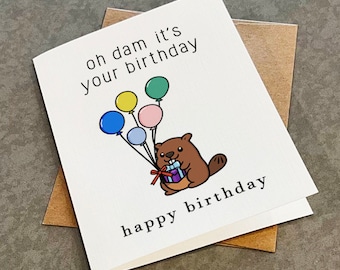 May include: A white card with the text "oh dam it's your birthday" and a cartoon beaver holding a gift box with balloons in the background. The text "happy birthday" is at the bottom of the card.