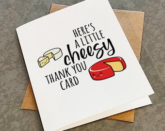 May include: A white card with the text "Here's a little cheesy thank you card" in black. The card features a cartoon illustration of a wedge of red cheese with a smiling face and a wedge of white cheese with a smiling face.