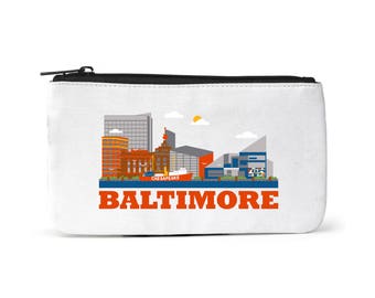 Puede incluir: Bolsa de lona blanca con cremallera con una ilustración colorida del horizonte de Baltimore, incluyendo el puerto interior, y el texto "BALTIMORE" en letras rojas.