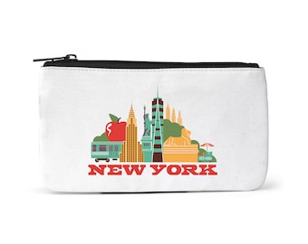 Puede incluir: Una bolsa blanca con cremallera que muestra una ilustración colorida del horizonte de la ciudad de Nueva York, incluyendo el Empire State Building, el Chrysler Building y la Estatua de la Libertad. El texto "NEW YORK" está impreso en rojo debajo de la ilustración.