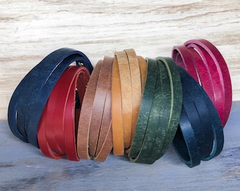 May include: A collection of leather strips in various colors, including navy blue, red, brown, tan, green, and pink. The strips are arranged in a circle, with the ends overlapping.