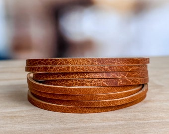 May include: A stack of brown leather strips, likely for crafting or jewelry making.