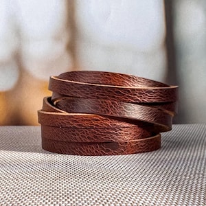 May include: A stack of brown leather strips, likely for crafting or leatherworking projects.