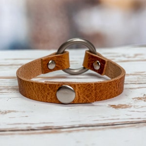 Snap closure on leather cuff bracelet with 1" antique brass ring.