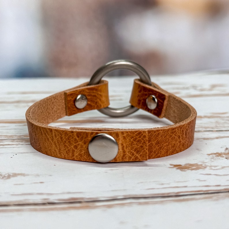 Snap closure on leather cuff bracelet with 1" antique brass ring.