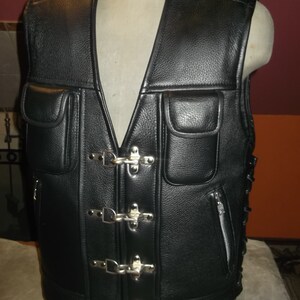 May include: Black leather vest with multiple silver buckles and a zippered pocket. The vest has a lace-up detail on the back.