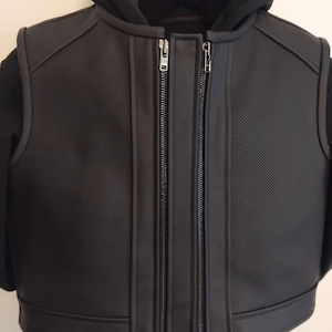 Puede incluir: Chaleco de cuero negro con cierre de cremallera y una sudadera con capucha negra debajo. El chaleco tiene un diseño perforado y una cremallera doble.