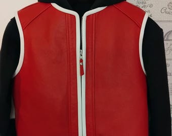 May include: A red leather vest with a white zipper and white trim around the edges. The vest is unzipped and has a black hoodie underneath.