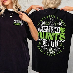 May include: Black t-shirt with a green graphic print that says "Emo Aunts Club" on the back. The front of the shirt has a smaller green graphic print that says "Emo Aunt".