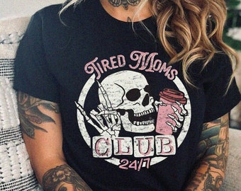 May include: Black t-shirt with a white skull and crossbones graphic. The graphic says "Tired Moms Club 24/7".