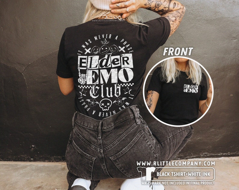 May include: Black t-shirt with white text that reads "It was never a phase Elder Emo Club". The text is surrounded by a skull and crossbones, flowers, and stars. The shirt is being modeled by a person with tattoos.