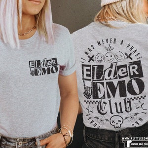 May include: Gray t-shirt with black text that reads "It was never a phase" and "Elder Emo Club". The text is in a distressed font and includes a skull and crossbones graphic.