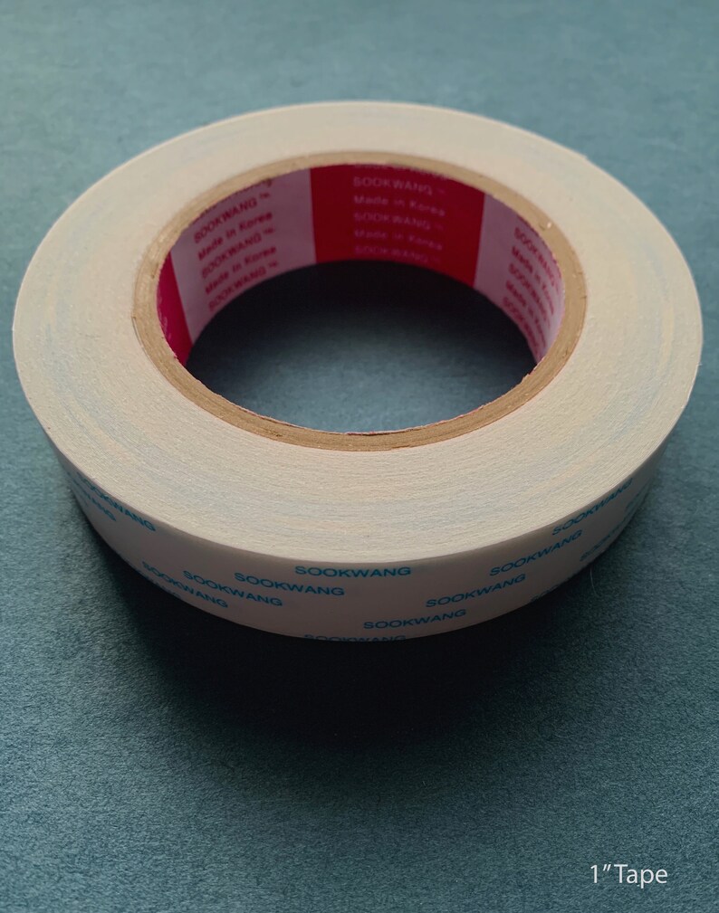 Pu&ograve; includere: Un rotolo di nastro adesivo a doppio lato bianco con testo blu e rosso che recita "SOOKWANG Made in Korea" e "1" Tape.