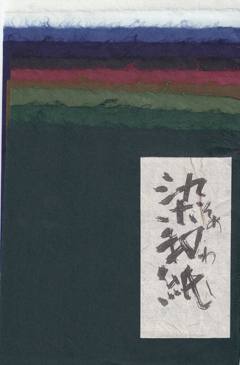 Pode incluir: Uma pilha de folhas de papel artesanais em v&aacute;rias cores, incluindo azul, bord&ocirc; e verde. Uma etiqueta branca com caligrafia japonesa est&aacute; no lado direito da pilha. O papel tem uma superf&iacute;cie texturizada e irregular.