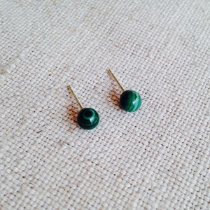 May include: A pair of green malachite stud earrings with silver posts.