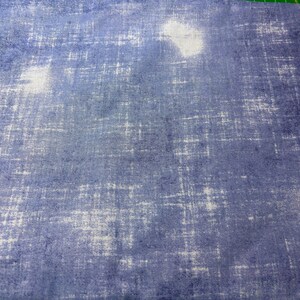 May include: A piece of fabric with a textured, mottled appearance. The fabric has a blue and white color scheme, with a pattern of intersecting lines and irregular shapes. The overall effect is reminiscent of a watercolor painting.