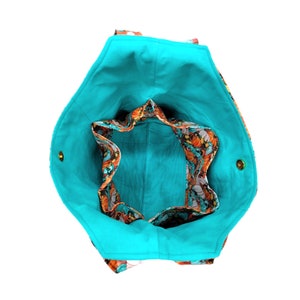 May include: A turquoise tote bag with a floral print lining. The bag has two gold-coloured buttons on the sides.