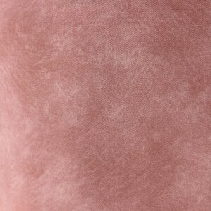 May include: Close-up of a dusty rose fabric with a textured appearance. The material has a slightly faded look, with lighter areas creating a subtle pattern across the surface. The fabric appears to be a soft, woven textile.