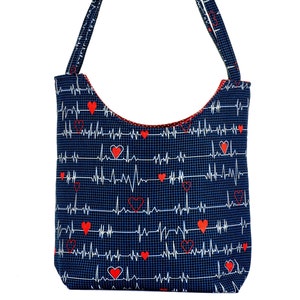 Peut inclure: Un sac cabas bleu avec un motif de battement de c&oelig;ur rouge et blanc. Le sac a une longue bandouli&egrave;re et une fermeture &agrave; glissi&egrave;re.