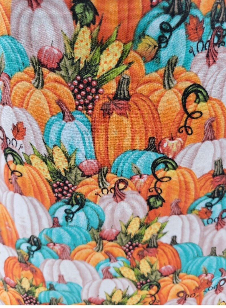May include: A colourful fabric featuring a pattern of orange, white, and teal pumpkins. The pumpkins are arranged in a random pattern and are surrounded by green leaves, corn, and grapes.