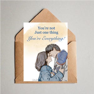 May include: A greeting card featuring an illustration of two people embracing, with the text 'You're not Just one thing You're Everything!' in blue. The card is tucked into a brown paper envelope. The illustration shows a person with dark hair and a person with curly hair wearing a blue and orange jersey with the number 44.