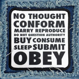 May include: A white patch with black text on a blue denim background. The text reads "No Thought Conform Marry Reproduce Do Not Question Authority Buy Consume Sleep Submit Obey".