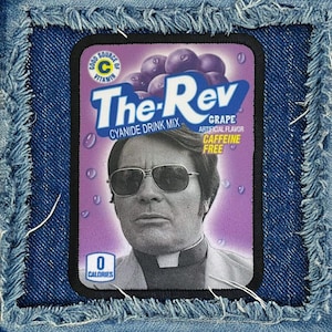 May include: A denim patch with a rectangular image featuring a man in sunglasses and the text "The Rev Grape Cyanide Drink Mix." The image includes purple grapes and the words "Caffeine Free" and "0 Calories."