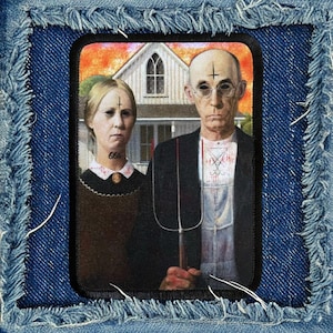May include: A black and white patch with a painting of a couple standing in front of a house. The man is wearing a white shirt and a black jacket. The woman is wearing a brown dress. The painting is a parody of the famous American Gothic painting.