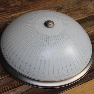 May include: A dome-shaped ceiling light fixture with a frosted white glass shade featuring a repeating dark line pattern radiating from the center. The fixture is secured by a central metallic cap and has a brushed silver metal base rim.