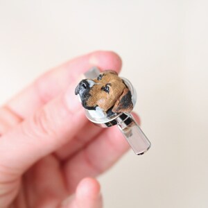 May include: A silver tie clip with a brown and white dog head sculpted on top.