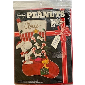 May include: A Peanuts "Jeweled" Christmas stocking kit in a plastic package. The stocking features Snoopy, a Christmas tree, and candy canes. The name "Chris" is embroidered on the stocking. The kit includes instructions and materials.