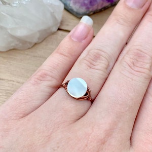 May include: A copper wire wrapped ring with a white mother of pearl stone.