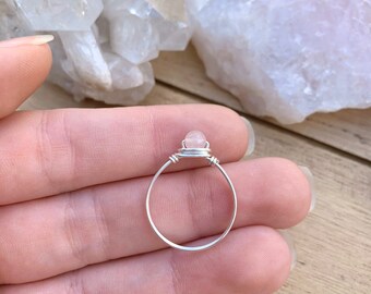 May include: A silver wire wrapped ring with a clear pink gemstone.
