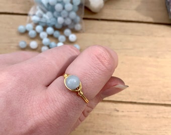Puede incluir: Un anillo de alambre dorado con una piedra preciosa azul claro.