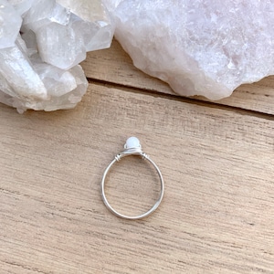 May include: A silver wire wrapped ring with a white gemstone.