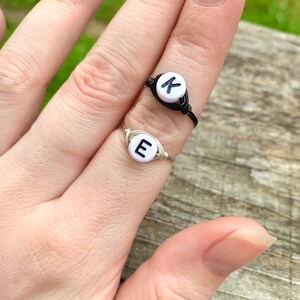 May include: Two wire wrapped rings with white beads. The beads have the letters "K" and "E" on them.