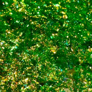 May include: Green glitter with iridescent shimmer. The glitter is densely packed and creates a sparkling effect.