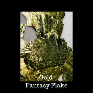 May include: Gold Fantasy Flake, a collection of thin, irregular, gold-colored flakes. The flakes are scattered on a white surface.