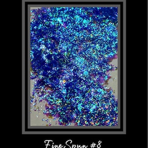 May include: Fine iridescent blue and green glitter, with a slight purple hue, scattered on a white surface. Fine Spun #8.