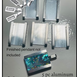 May include: Five silver modern bails and five aluminium Fusion Bezel settings for making a pendant. The bezels are rectangular and have a brushed finish. The bails are small and have a textured finish. Finished pendant not included.