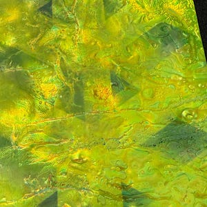 May include: A textured surface featuring a vibrant blend of lime green and bright yellow hues. The material displays a glossy, uneven finish with raised, organic patterns and subtle geometric shapes visible beneath the translucent, liquid-like layers.