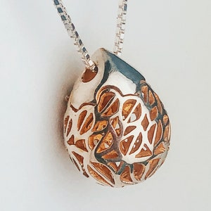 flowers cut from a silver drop, which opens to insert a message or an aromatherapy bead. treasure cache pendant