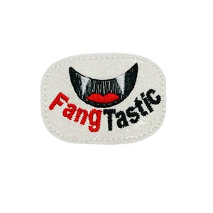 May include: White iron-on patch with a black and red embroidered image of a vampire's mouth with fangs and the text "Fangtastic".